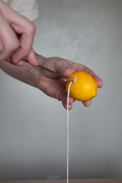 Push an end of the butcher twine through the first lemon.